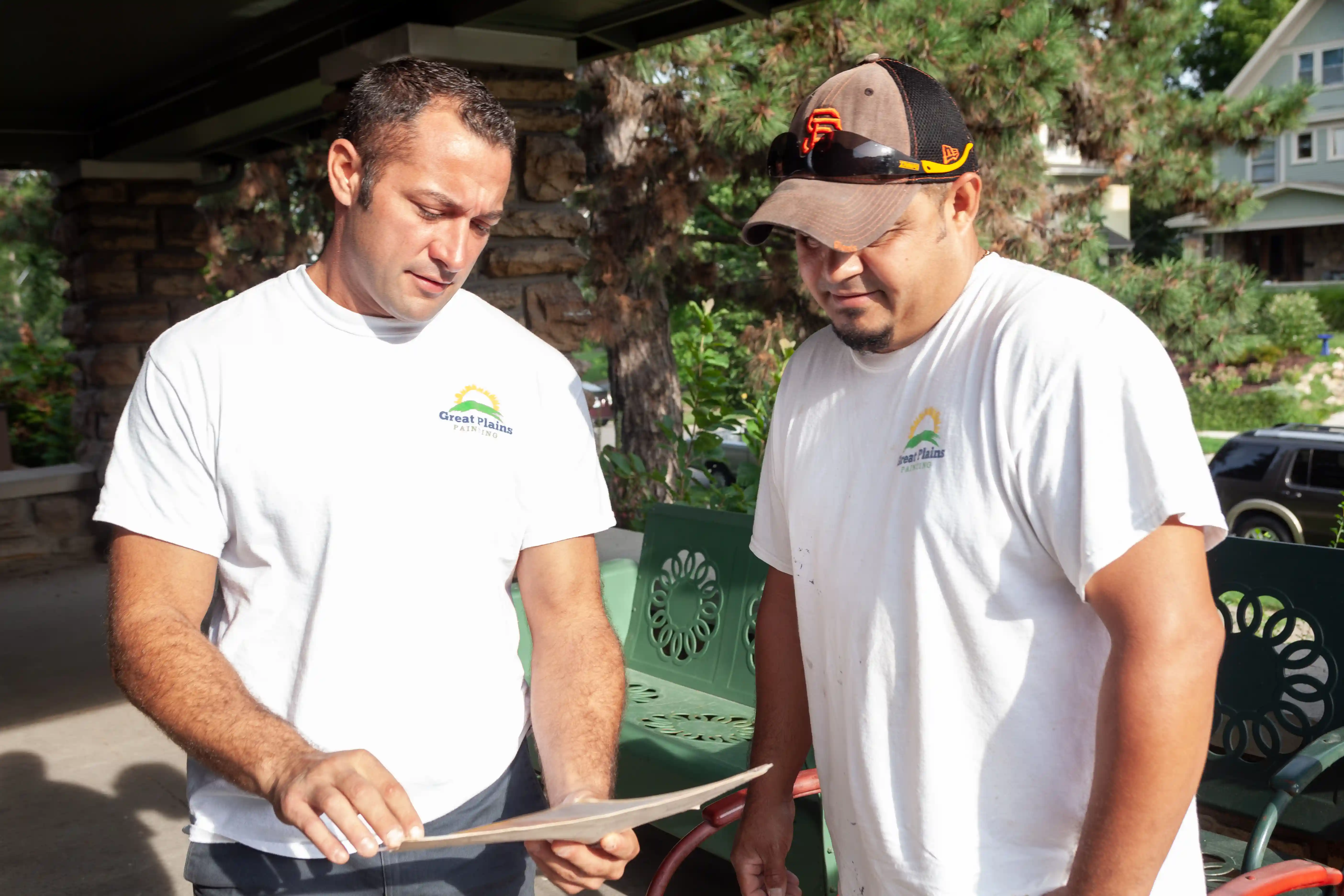 A team of two painters reviewing project details on the front porch of a Kansas City home.